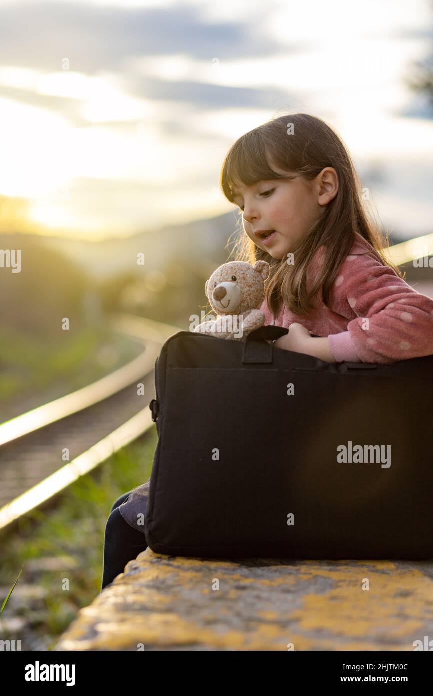 Das kleine Mädchen spricht auf dem Bahnsteig mit ihrem Teddybären Stockfoto