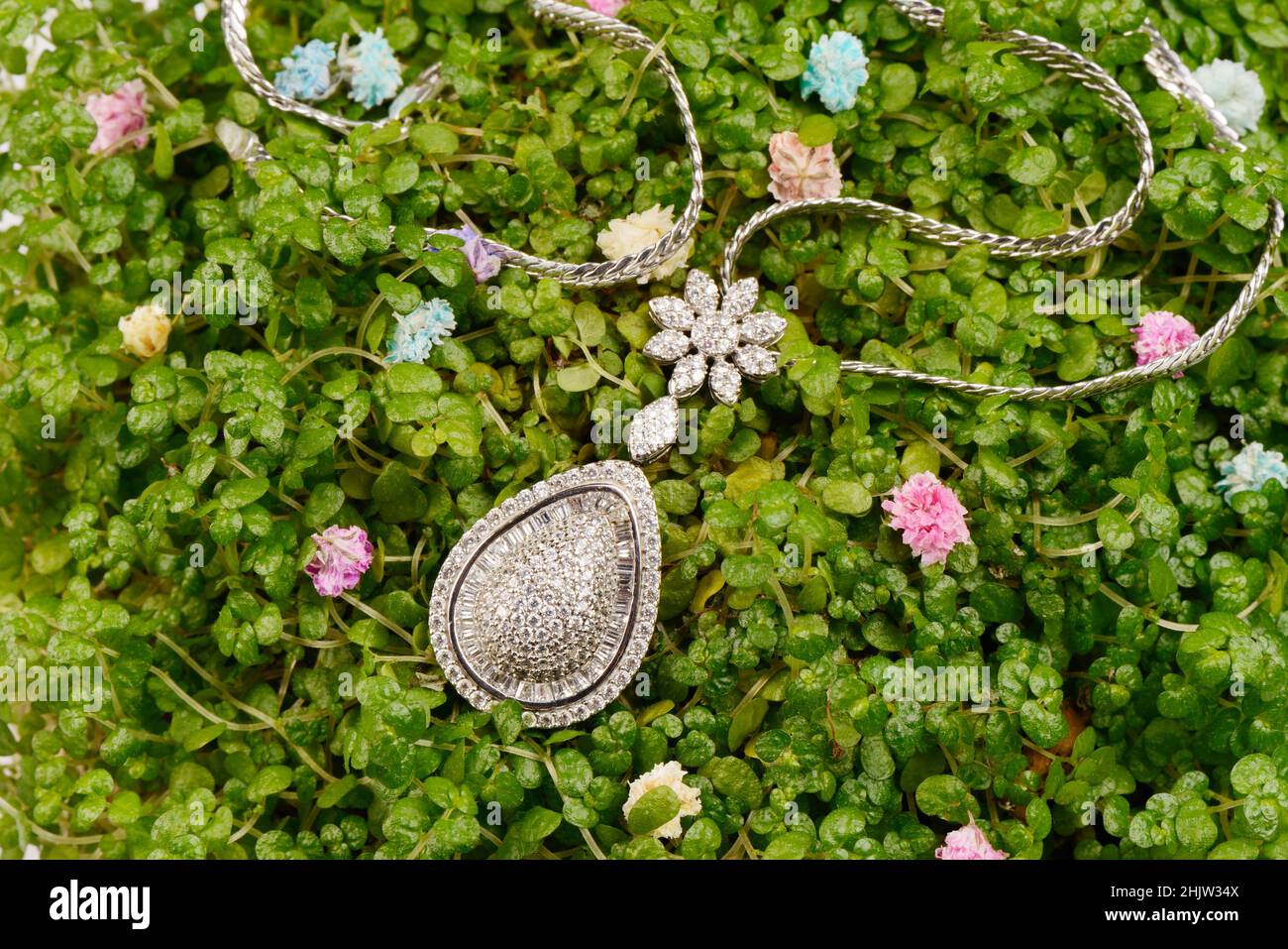 Damen Platin Anhänger mit Diamanten, auf ein wenig grünen Blättern, Mikro. Luxuriöser weiblicher Schmuck Stockfoto