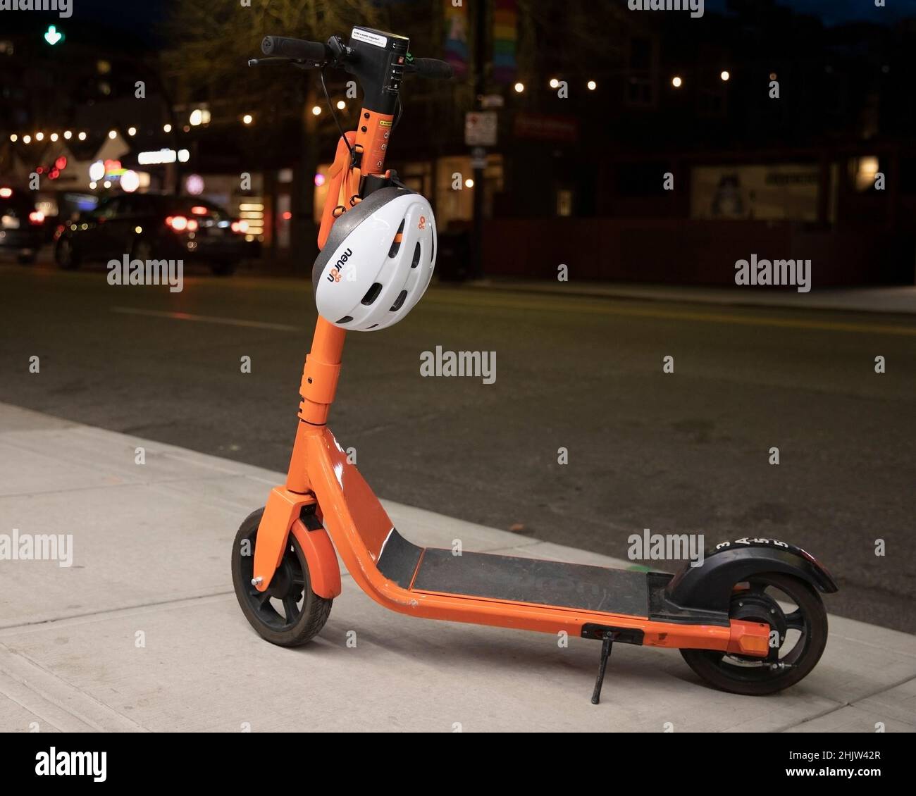 Geteilter E-Scooter, der nachts auf einem Bürgersteig geparkt wurde, mit dem weltweit ersten App-gesteuerten Helmschloss, das bei jeder Vermietung einen Sicherheitshelm bietet. Stockfoto