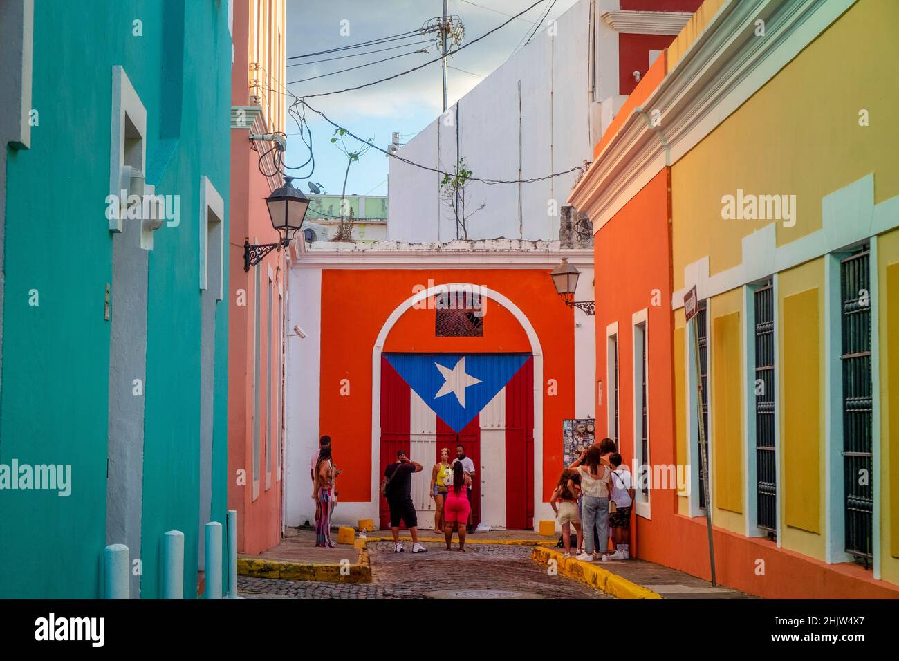 Touristen neben einem Wandbild der Puerto-ricanischen Flagge in einer Straße voller farbenfroher Häuser, Old San Juan, Puerto Rico Stockfoto