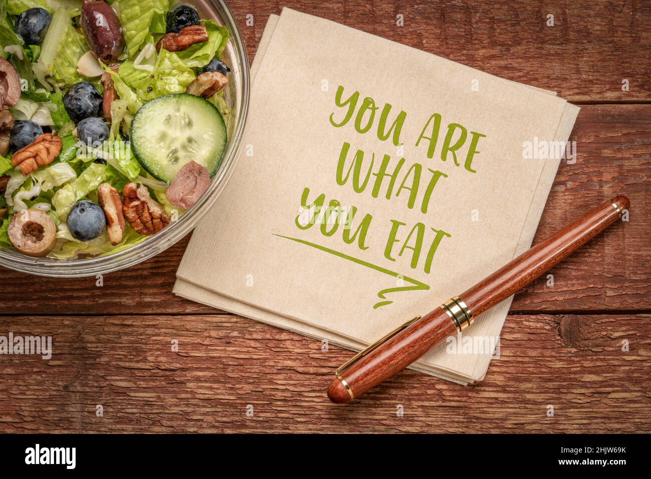 Gesundes Essen und Lifestyle-Konzept - Sie sind, was zu essen Erinnerungsworte handgeschrieben auf einer Serviette mit einer Schüssel Salat Stockfoto