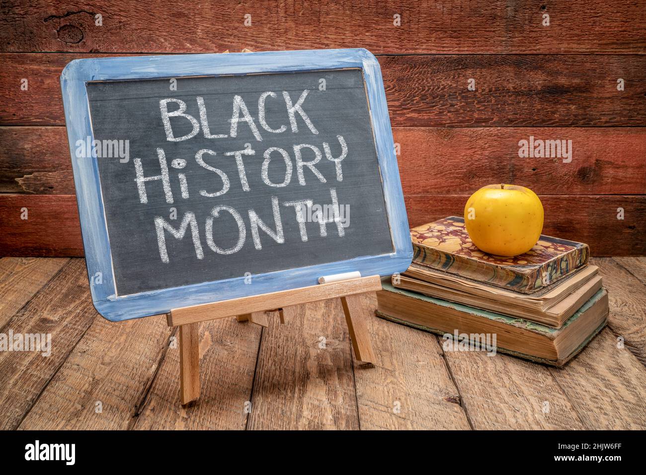 Black History Month, weiße Kreidehandschrift auf einer Schiefertafel gegen rustikales Holz mit Büchern, jährliche Einhaltung mit Ursprung in den Vereinigten Staaten Stockfoto