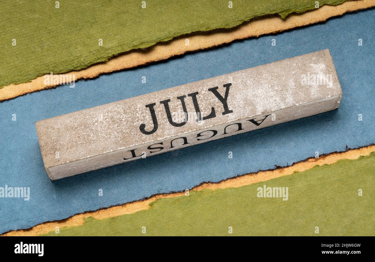 Juli Text auf grunge Holzblock gegen handgefertigtes Lapppapier in Blau- und Grüntönen, Kalenderkonzept Stockfoto