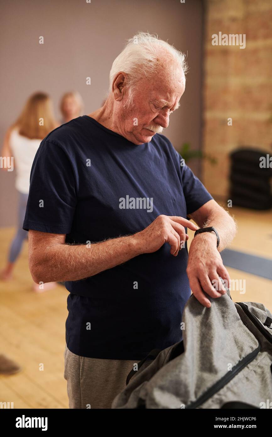 Älterer Mann, der nach dem Sporttraining im Fitnessstudio die Indikatoren auf dem Fitnessarmband überprüft Stockfoto