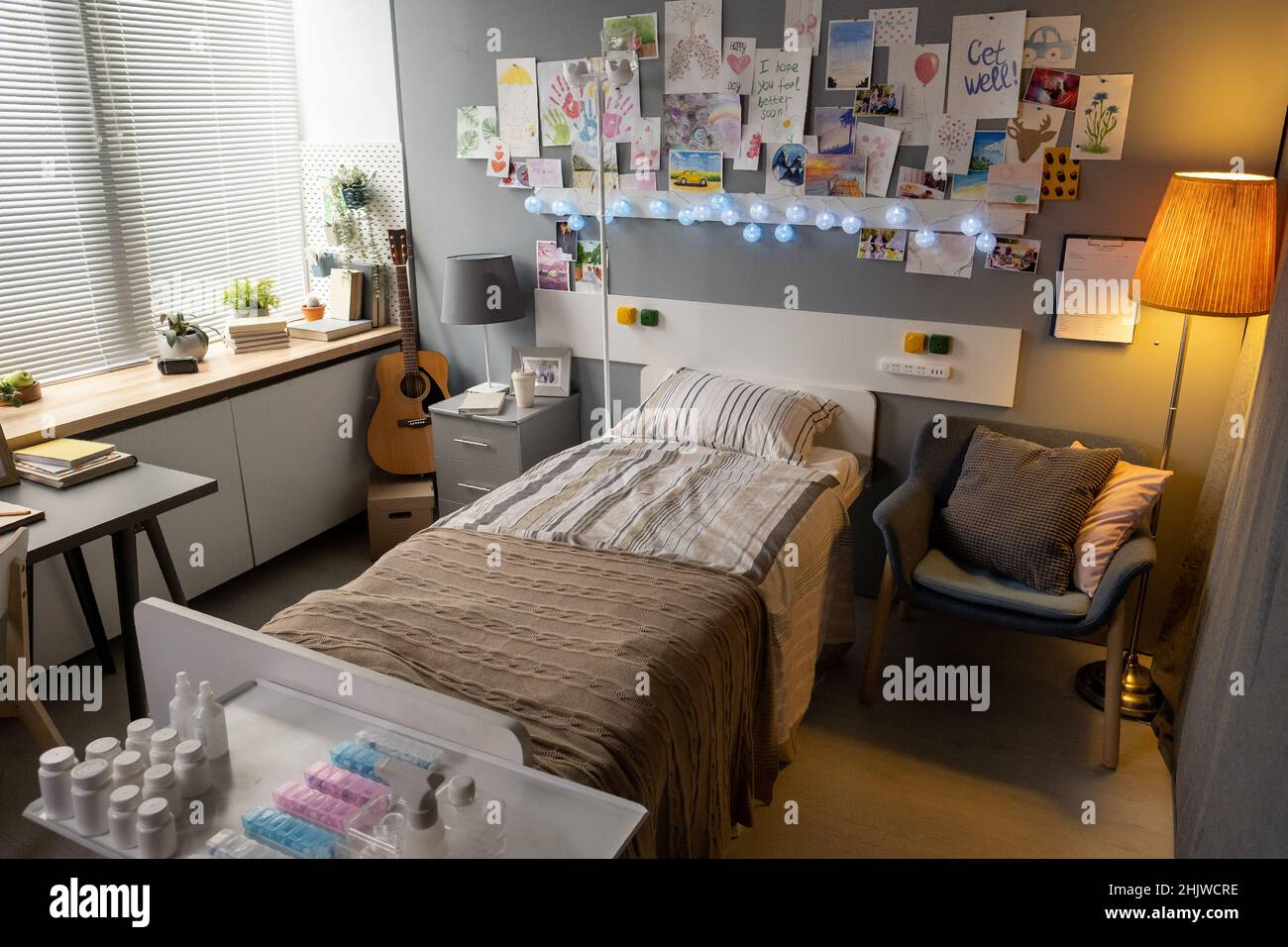 Bild vom Krankenhausbett mit gemalten Bildern, die an der Wand hängen, und Medizin auf dem Nachttisch auf der Station Stockfoto