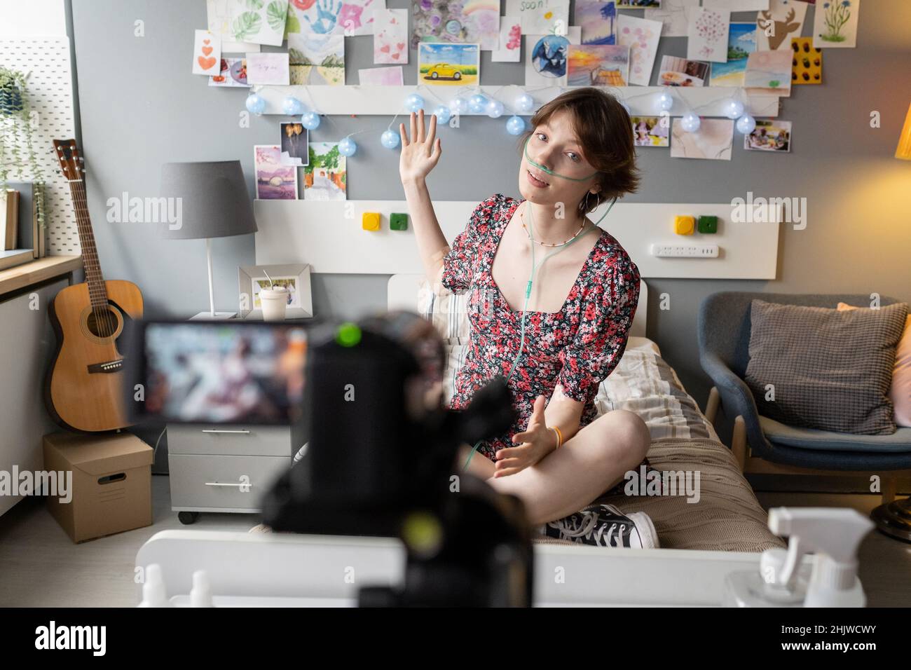 Eine junge Frau zeigt ihre Zeichnungen an der Wand, während sie auf der Krankenstation für ihre Anhänger den Blog dreht Stockfoto