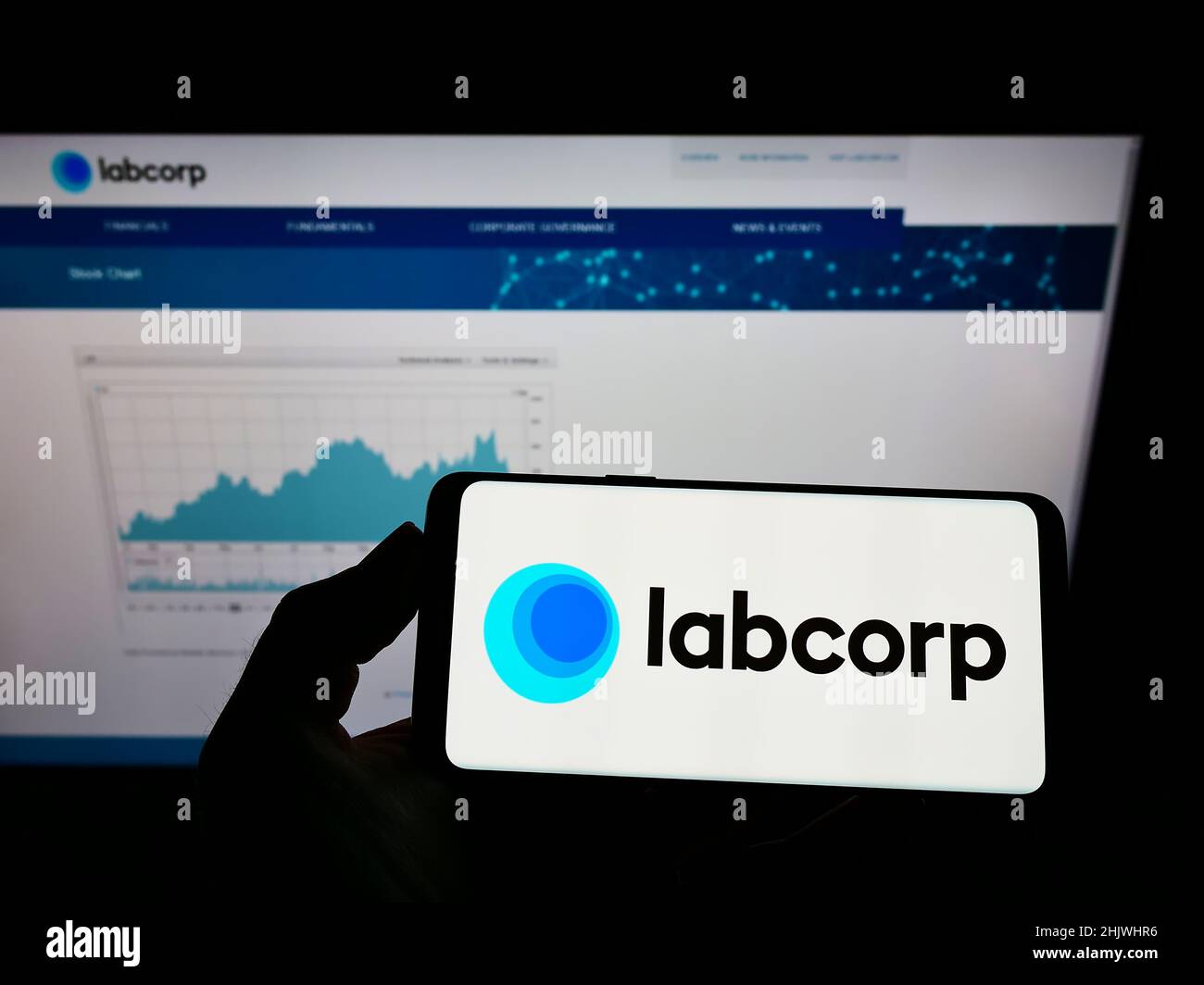 Person, die das Mobiltelefon mit dem Logo des amerikanischen Laborunternehmens LabCorp auf dem Bildschirm vor der Business-Webseite hält. Konzentrieren Sie sich auf die Telefonanzeige. Stockfoto