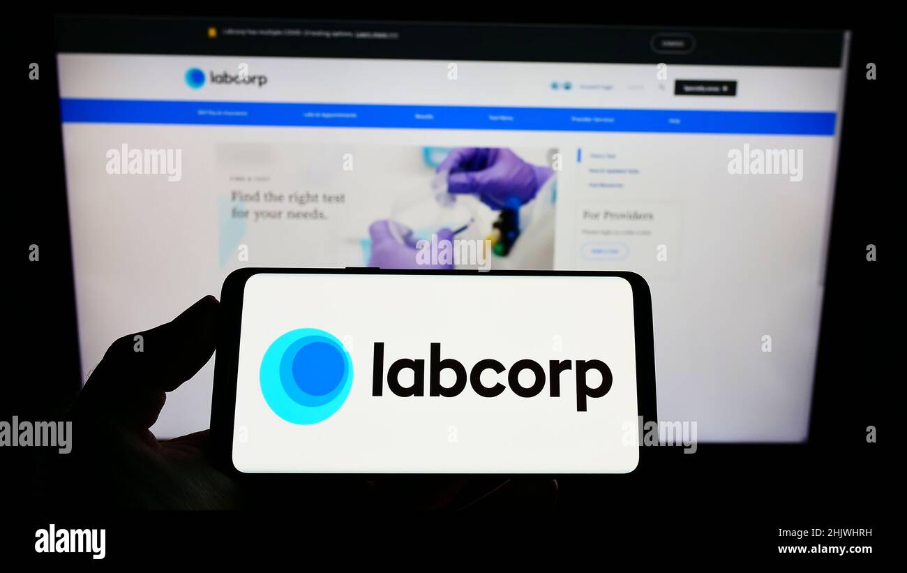 Person, die Mobiltelefon mit dem Logo des US-Laborunternehmens LabCorp auf dem Bildschirm vor der Business-Webseite hält. Konzentrieren Sie sich auf die Telefonanzeige. Stockfoto
