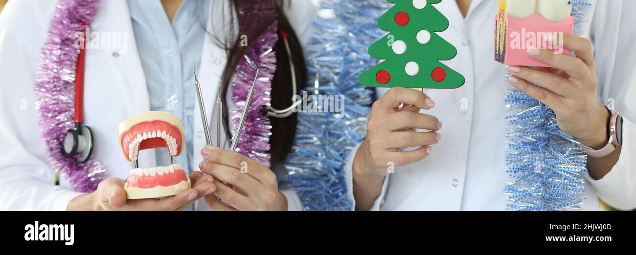 Zwei Zahnärzte halten ein Zahninstrument auf dem Hintergrund des Weihnachtsbaums in der Hand Stockfoto