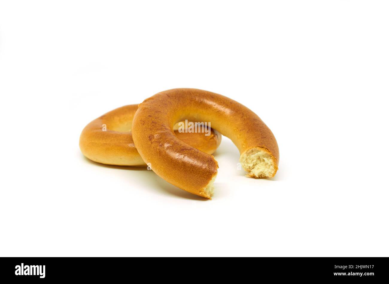 Ganze und gebissene Bagels auf weißem Hintergrund Stockfoto