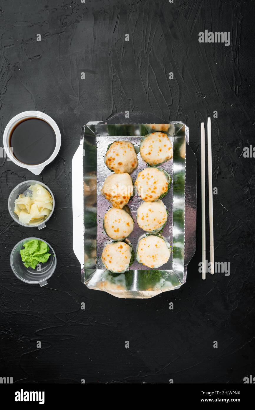 Sushi-Rollen im Take-away-Container-Set, auf schwarzem Steingrund, Draufsicht flach liegend, mit Copyspace und Platz für Text Stockfoto