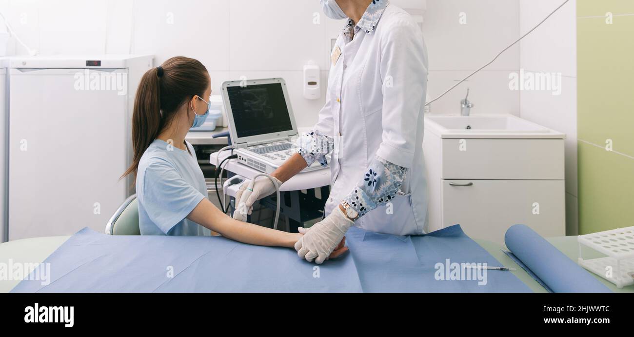 Arzt, der den Ultraschall an der Hand macht, Nahaufnahme. Der Arzt zeigt dem Patienten Ultraschallergebnisse. Medizinische Ultraschalluntersuchung. Rehabilitation Stockfoto