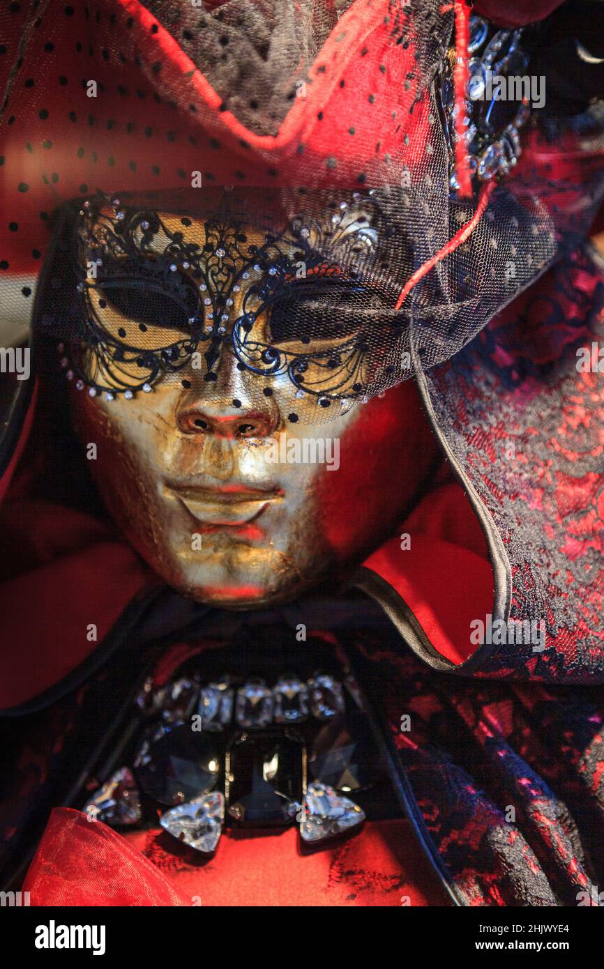 Verschleierte goldene Maske und traditionelles rotes Barock-Kostümkleid mit Hut und Umhang, Nahaufnahme. Karneval in Venedig, Carnevale di Venezia, Italien Stockfoto