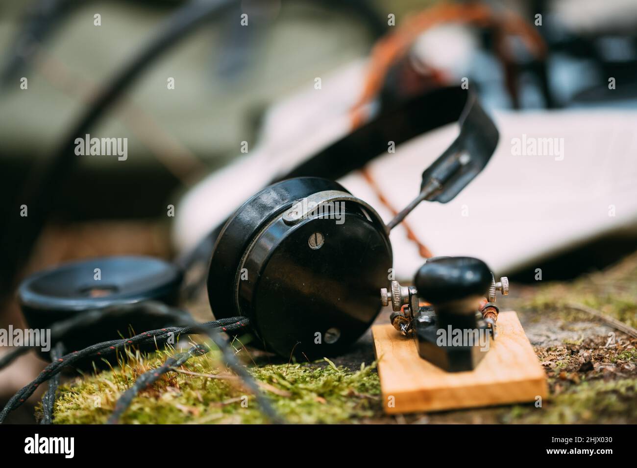 Russischer tragbarer Funkempfänger der sowjetischen Armee, der im Zweiten Weltkrieg vom Signalkorps der Roten Armee der UdSSR verwendet wurde. Kopfhörer und Telegraph Key befinden sich auf EINEM Waldstumpf Stockfoto