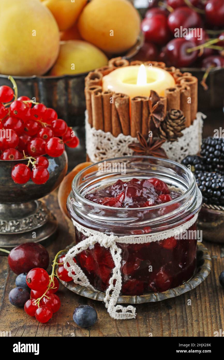 Gläser Kirschkerne Erdbeermarmelade zwischen Sommer und Herbst Früchte auf einem Holztisch. Stockfoto