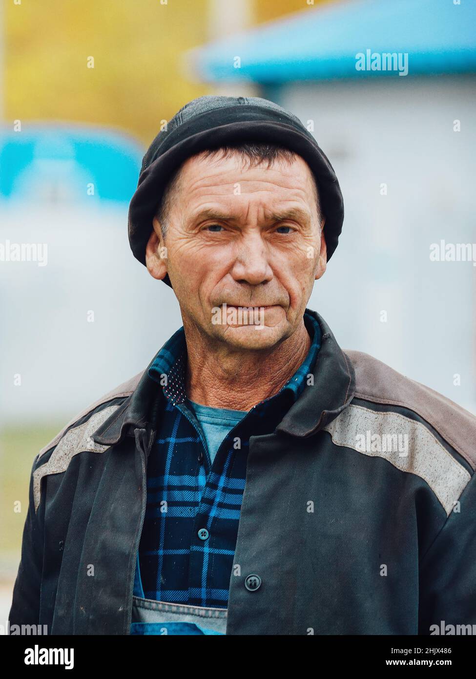 Brusthochporträt des arbeitenden Mannes. Echter müder Bauarbeiter in Arbeitskleidung steht auf der Straße und blickt direkt in die Kamera. Echte ernsthafte Schweißer 50-60 Jahre alt Stockfoto