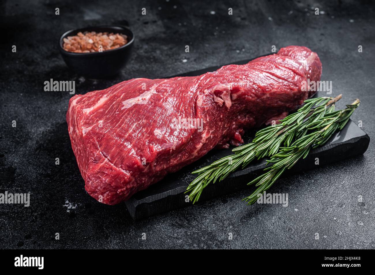 Rohes amerikanisches Tri Tip Beef Steak auf Marmorplatte. Schwarzer Hintergrund. Draufsicht Stockfoto