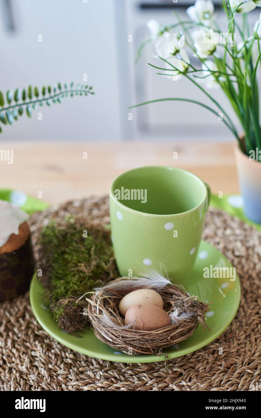 Osterdekorationen in der Küche mit Eiern im Nest und einer Tasse Tee. Stockfoto