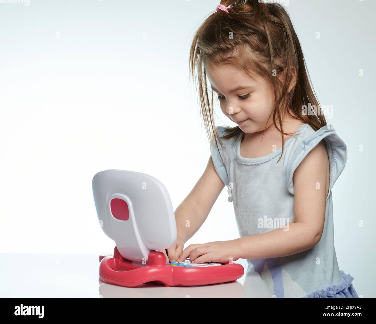 Kindertyp auf Spielzeug-Laptop isoliert auf weißem Studiohintergrund Stockfoto