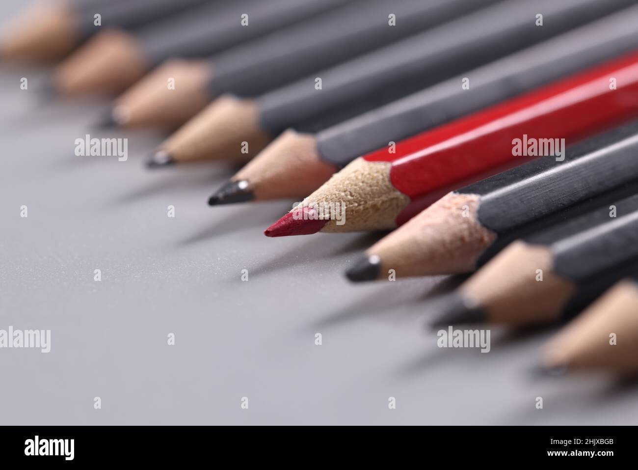 Nahaufnahme eines roten Holzbleistifts unter vielen schwarzen Hintergründen Stockfoto