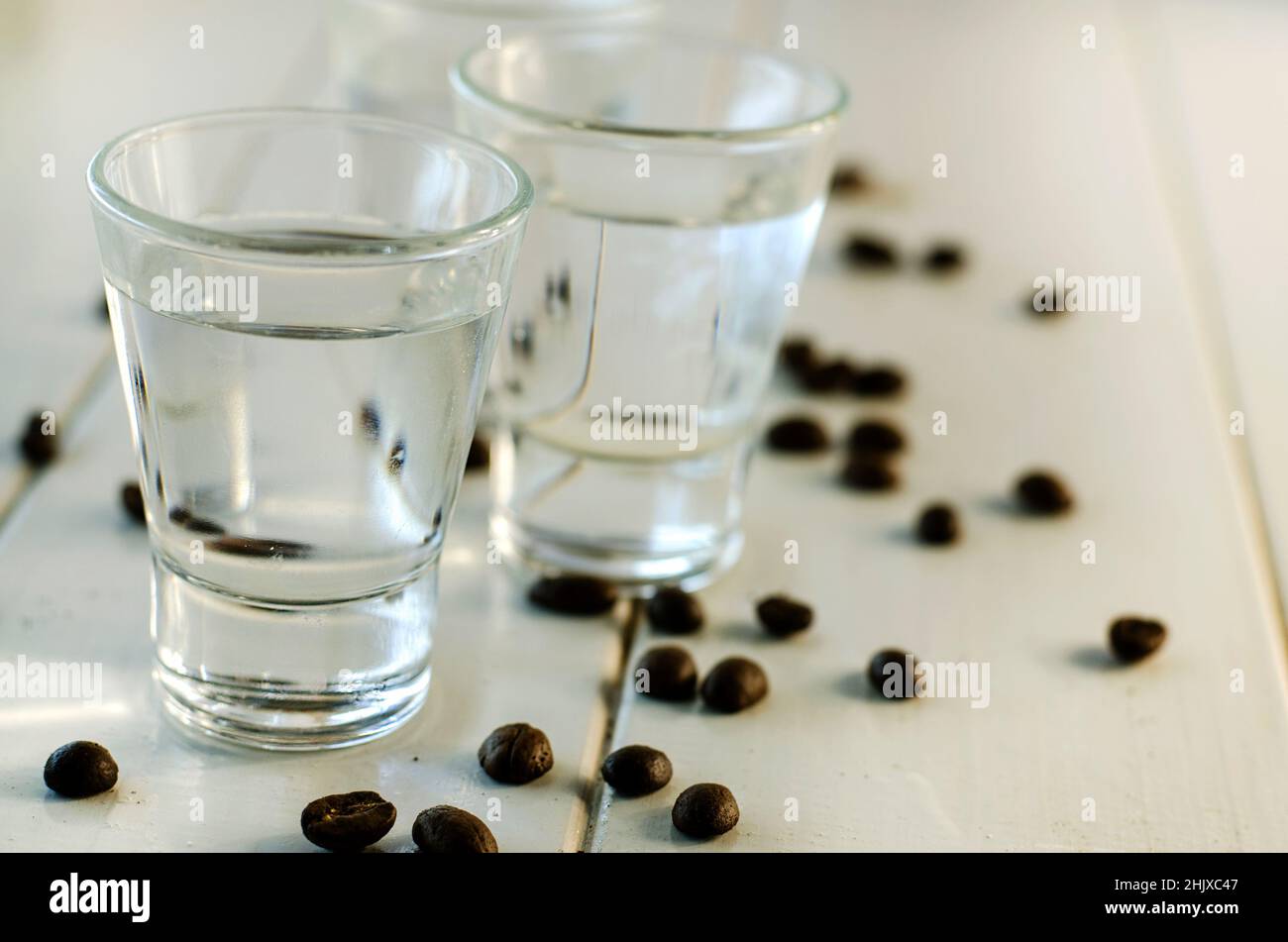 Sambuca in Schnapsgläsern und Kaffeebohnen auf weißem Hintergrund Stockfoto
