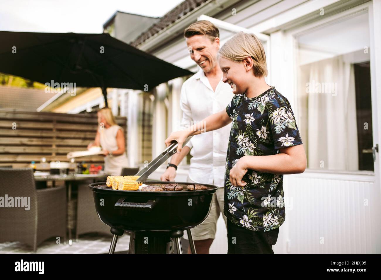 Sohn bereitet Grillmahlzeit mit Vater im Hinterhof zu Stockfoto
