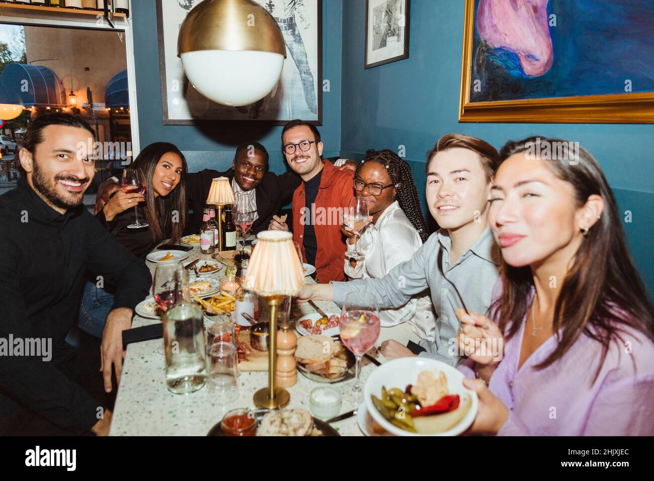 Porträt von lächelnden, multirassischen Freunden während der Dinner-Party in der Bar Stockfoto