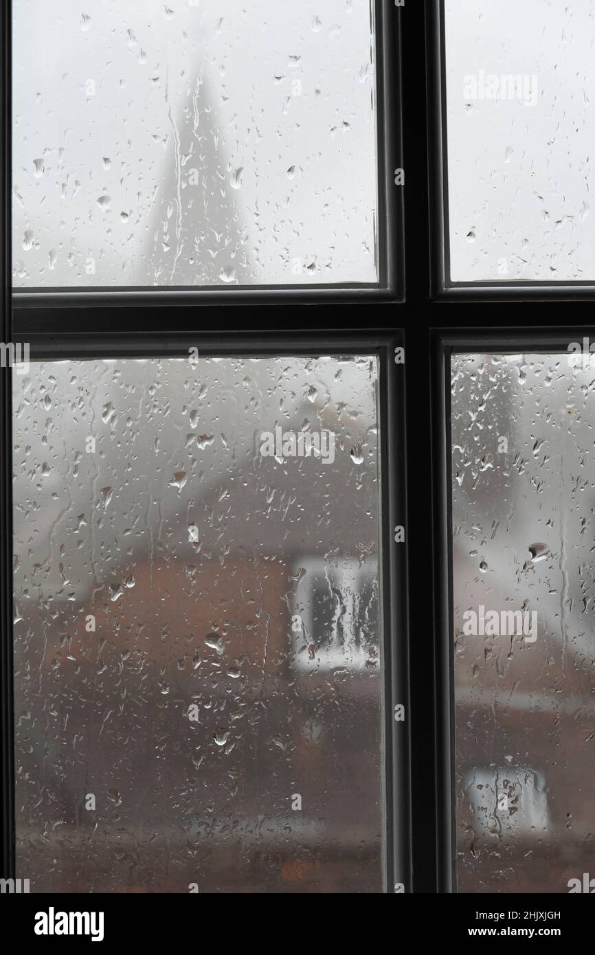 Regen auf Glasfensterscheibe mit Kirchturm im Hintergrund, Burwash, East Sussex, England, Vereinigtes Königreich, Europa Stockfoto