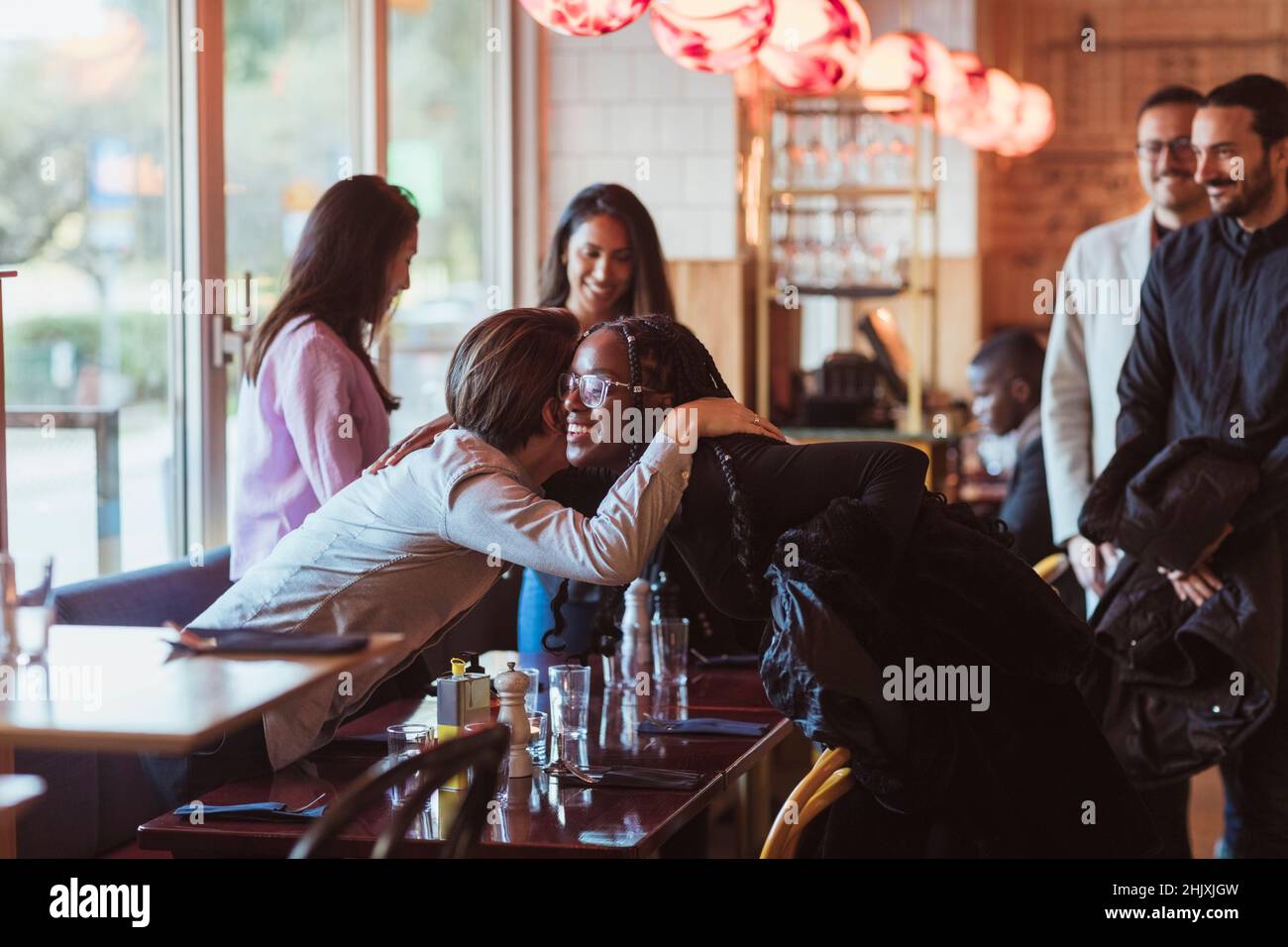Lächelnde Frau begrüßt männlichen Freund während der Party in der Bar Stockfoto