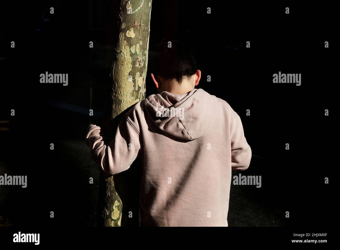 Junge lehnt sich an Baum, Barcelona, Spanien. Stockfoto