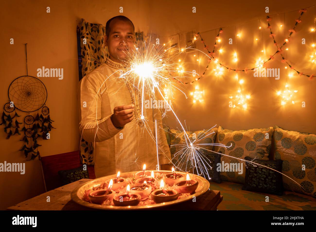 Junger Mann in traditioneller Kleidung hält das Feuerwerk in der Hand mit Fähre Lichter Hintergrundbild wird zur Feier der diwali aufgenommen. Stockfoto