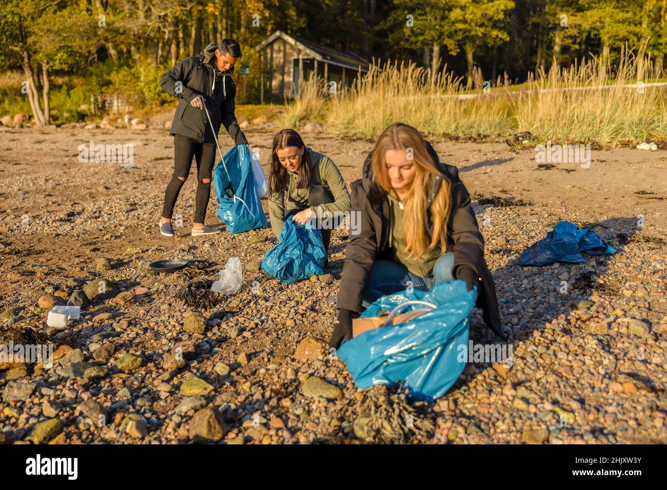 Eine Gruppe von Freiwilligen, die Plastikmüll am Strand und vom Meer abholen Stockfoto