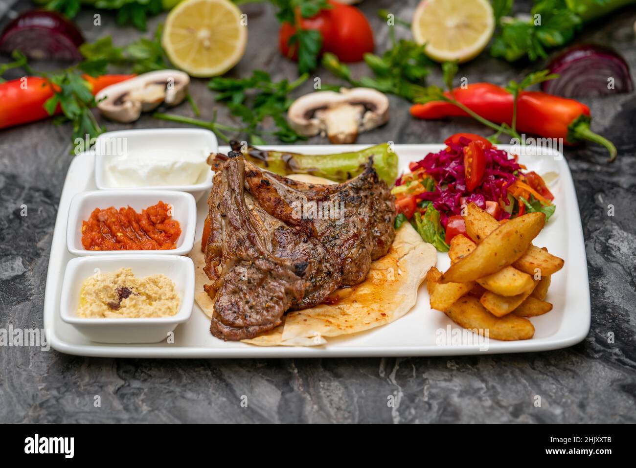 Gegrillte Lammkoteletts mit pommes Frites und Vorspeisen auf einem weißen Porzellanteller Stockfoto