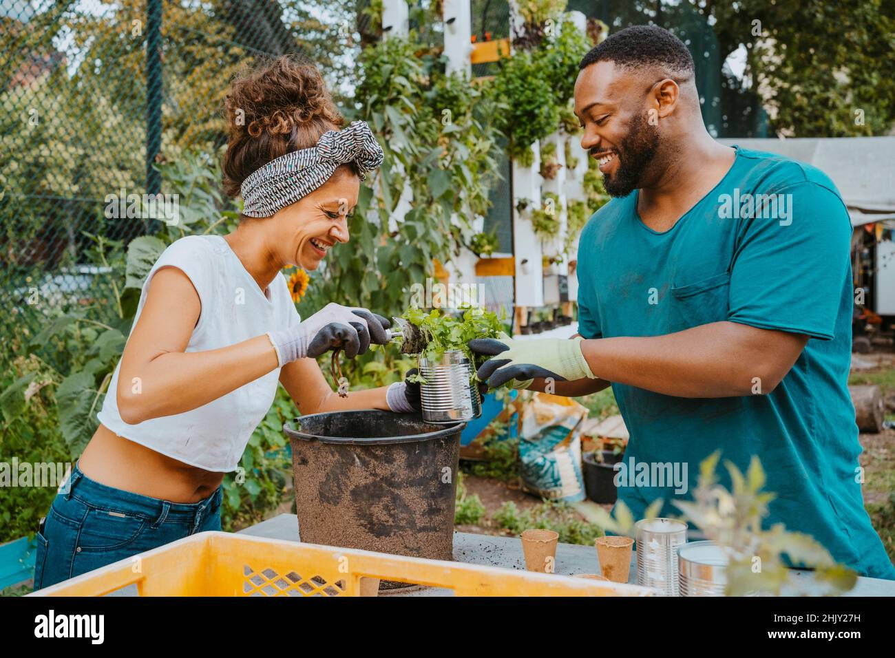 Glückliche männliche und weibliche Umweltschützer Pflanzen Blumen in Topf auf städtischen Bauernhof Stockfoto