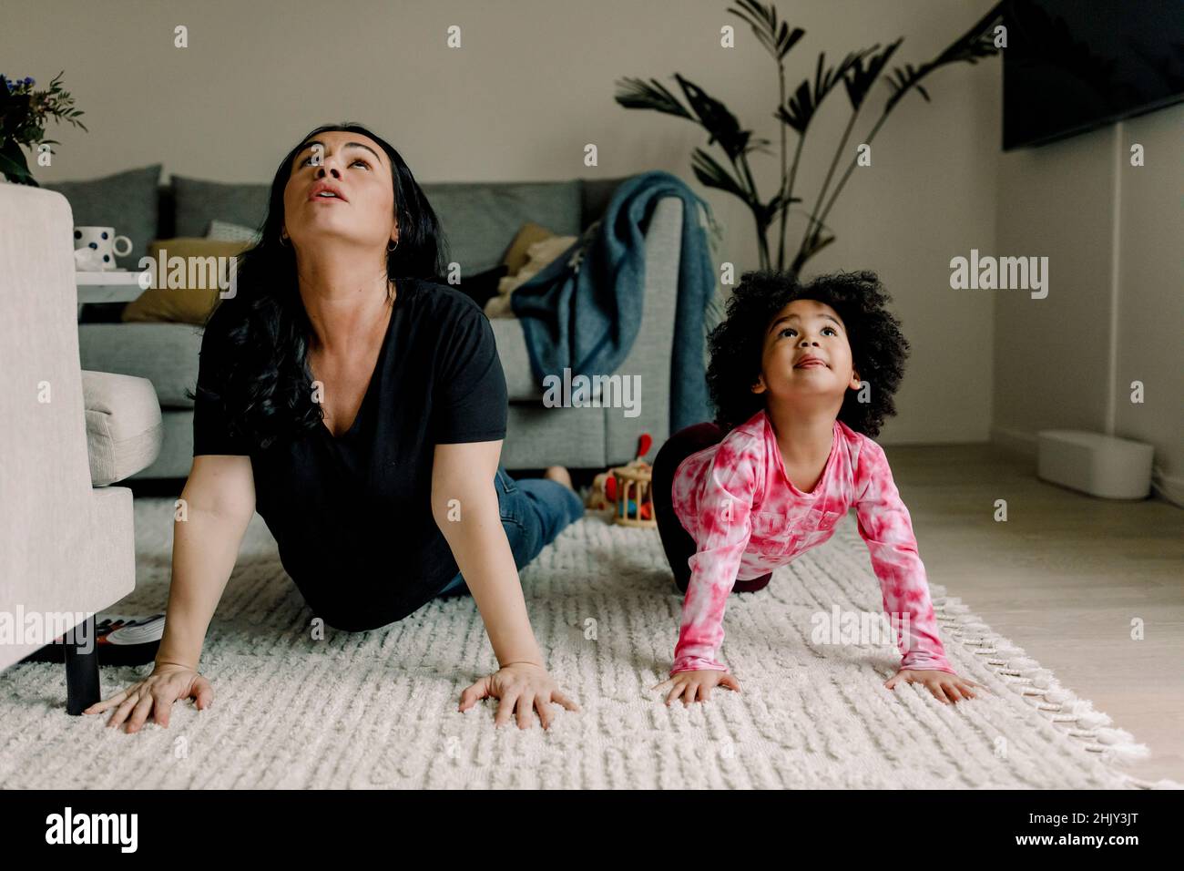 Mutter und Tochter praktizieren Yoga im Wohnzimmer zu Hause Stockfoto