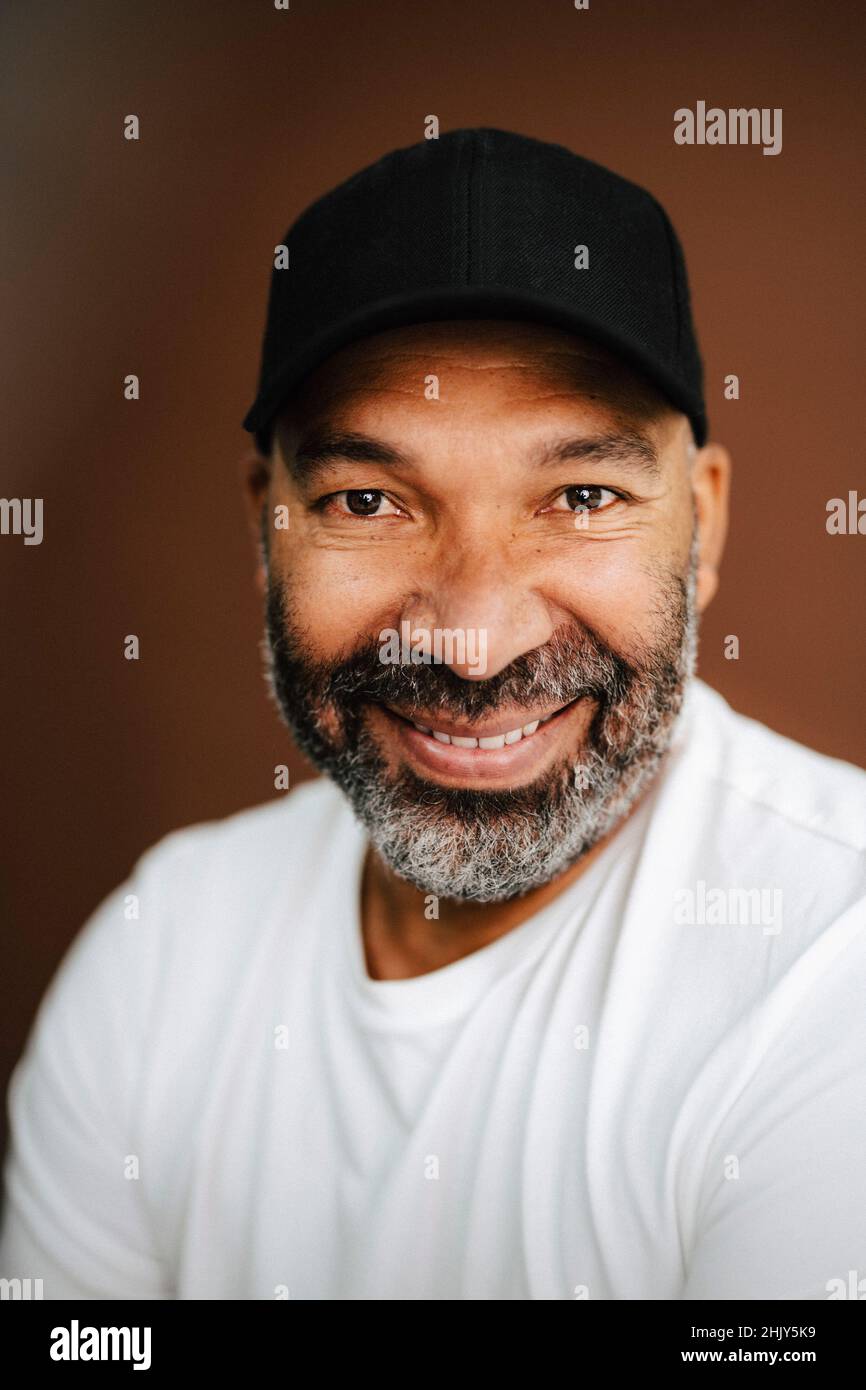 Lächelnder Mann mit Mütze vor braunem Hintergrund Stockfoto