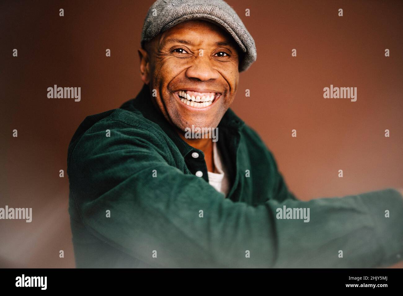 Fröhlicher reifer Mann mit braunem Hintergrund im Studio Stockfoto