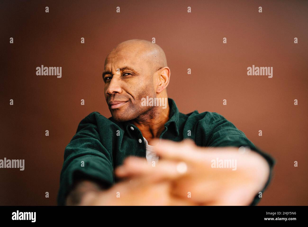 Glatze reifer Mann gestikuliert vor braunem Hintergrund Stockfoto