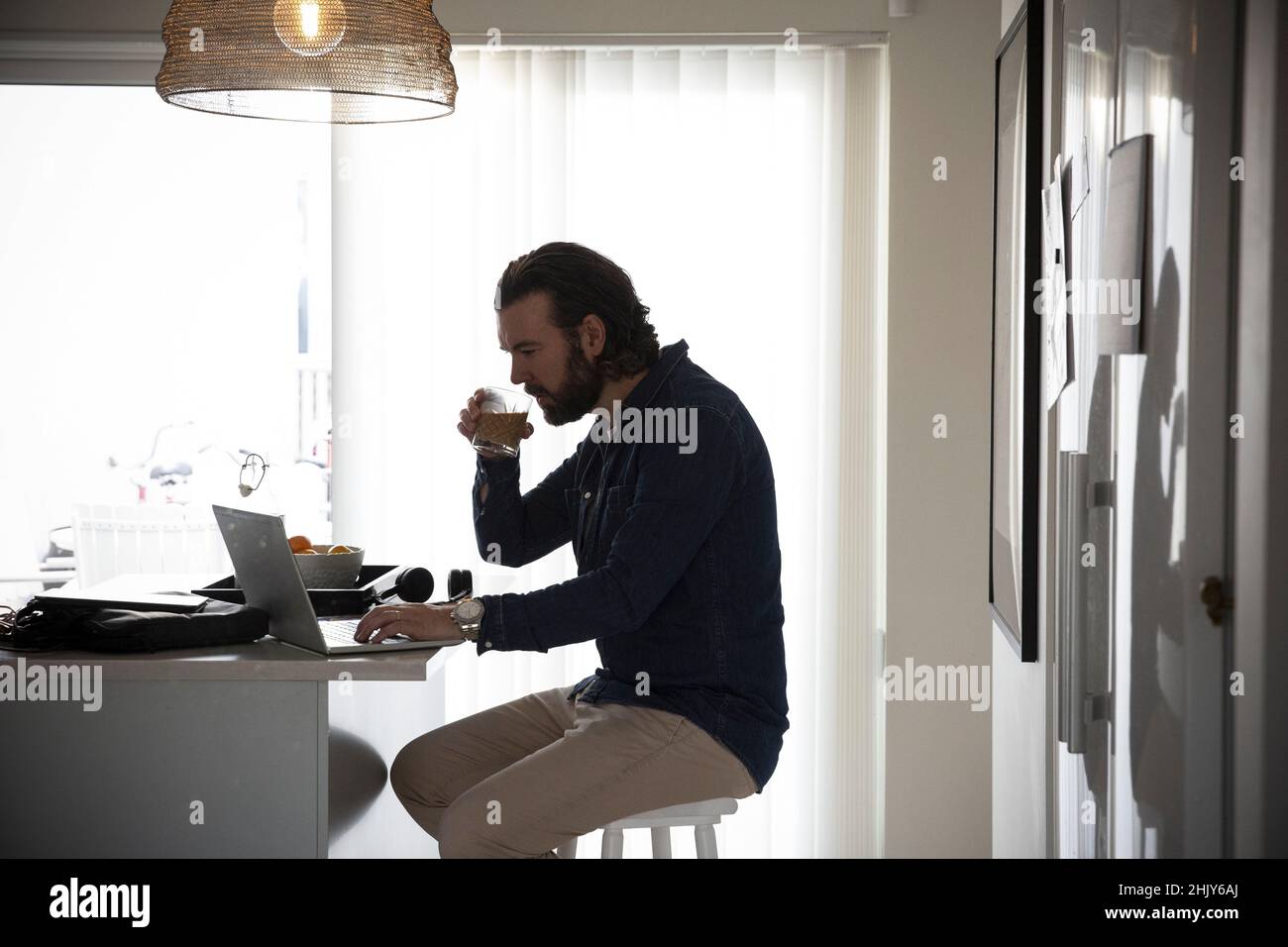 Freiberuflicher Mann, der Kaffee trinkt, während er zu Hause arbeitet Stockfoto