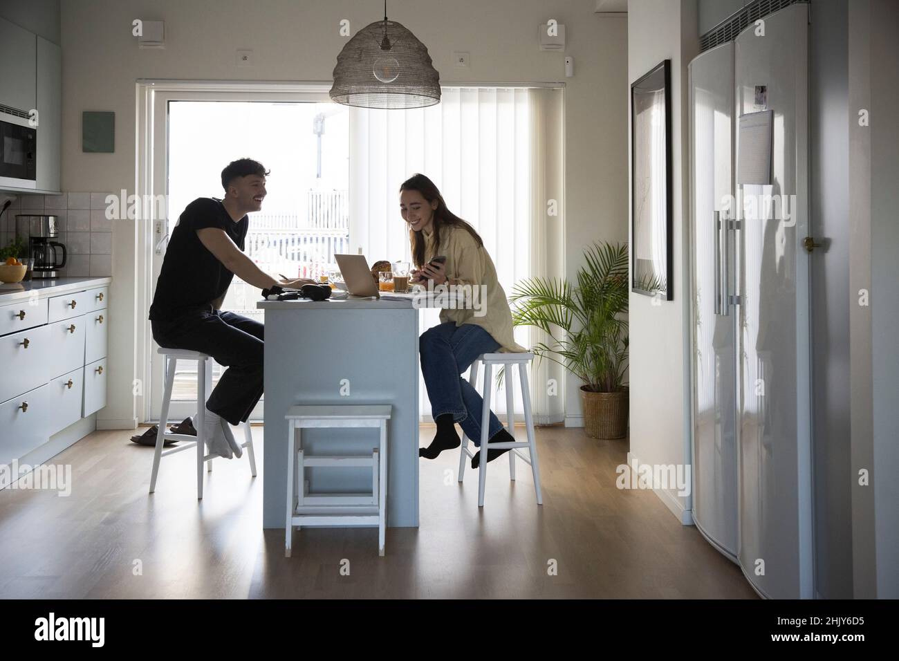 Lächelndes junges Paar, das in der Küche mit einem Laptop arbeitet Stockfoto