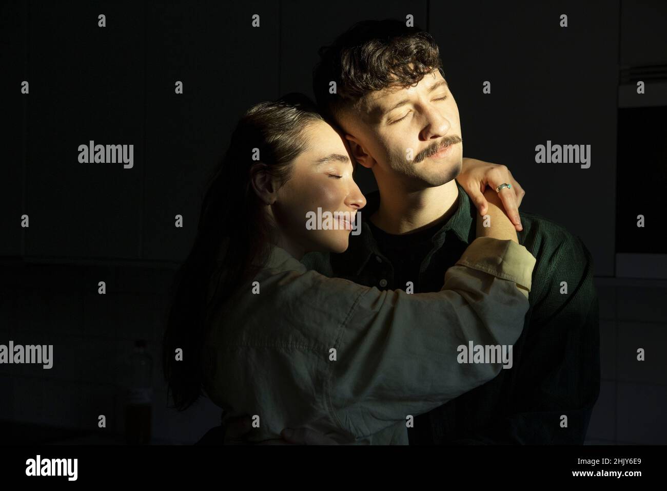 Freund und Freundin mit geschlossenen Augen umarmen zu Hause Stockfoto