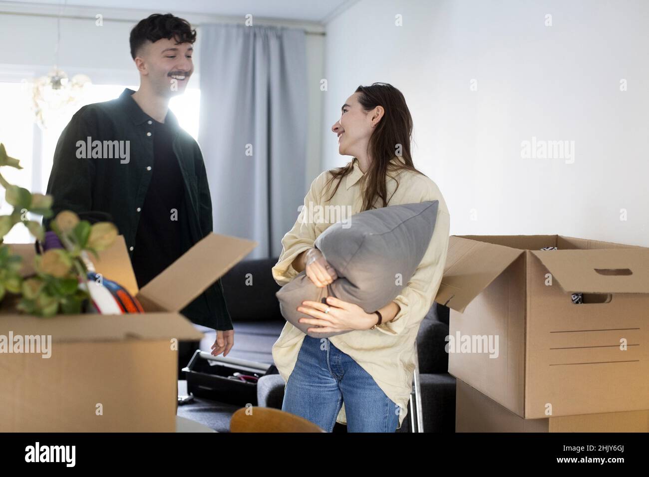 Lächelnder Mann, der mit seiner Freundin spricht, während er in ein neues Haus umzieht Stockfoto