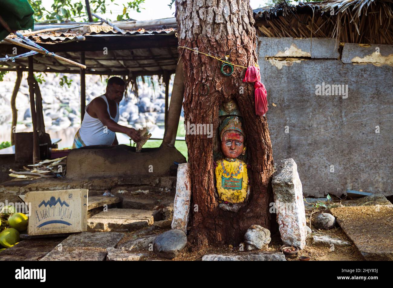 Hampi, Karnataka, Indien: Geschnitzter heiliger Baum am Fluss Tungabadra. Zufällige Personen im Hintergrund. Stockfoto