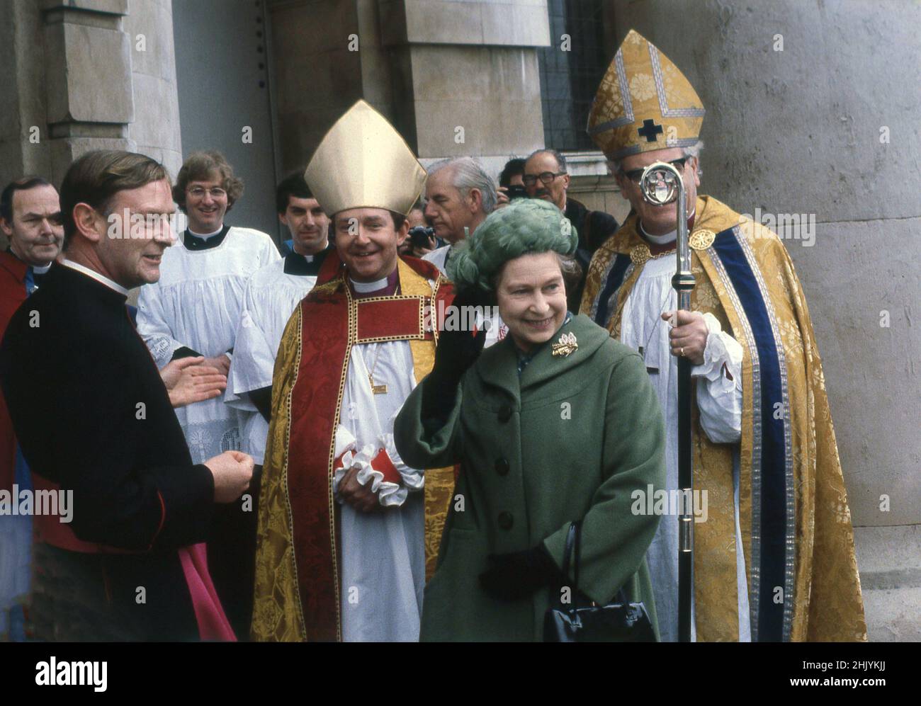 1977, historisch, hob ihre Majestät Königin Elizabeth II. Ihre Hand, um die Zuschauer vor der St. Pancras Kirche in der Euston Rd, London, England, Großbritannien, zu würdigen, die mit hochrangigen Geistlichen, darunter zwei Bischöfe in ihren religiösen Gewändern, Gewändern und Hüten, im Rahmen ihrer Silbernen Jubliee-Feierlichkeiten standen. Stockfoto