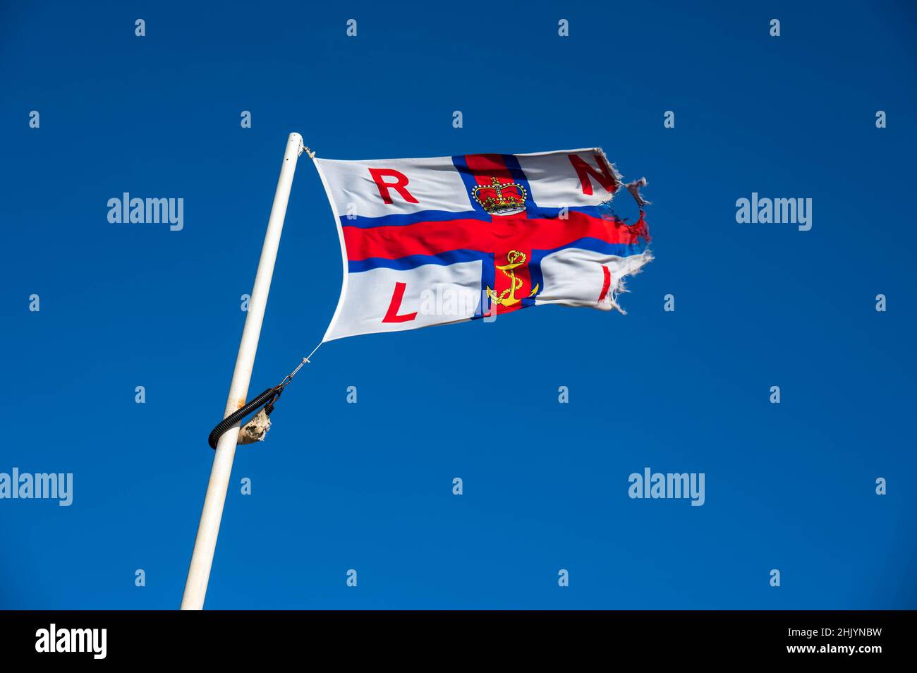 Eine abgenutzte RNLI-Flagge, die in den starken Winden an der Rettungsbootstation Cromer Norfolk weht Stockfoto