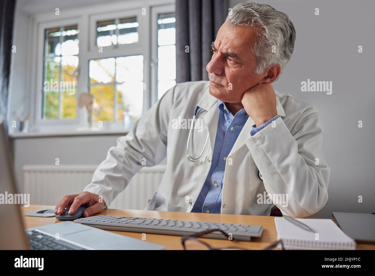 Gestresster Und Überarbeiteter Arzt Im Weißen Mantel Am Schreibtisch Im Büro Stockfoto