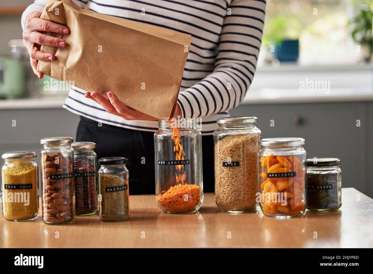 Frau Spart Beim Verpacken Durch Abfüllen Von Recycelten Jars, Um Getrocknete Lebensmittel Zu Hause Zu Lagern Stockfoto