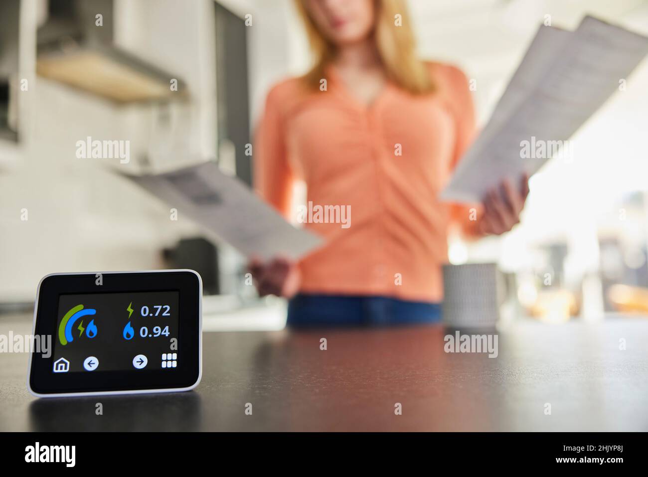 Nahaufnahme Eines Intelligenten Energiezählers In Der Küche, Der Strom- Und Gasnutzung Misst, Während Eine Frau Rechnungen Betrachtet Stockfoto