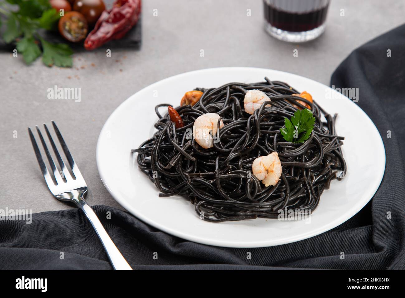Schwarze Pasta mit Meeresfrüchten auf weißem Teller auf Marmortisch Hintergrund. Selektiver Fokus. Stockfoto