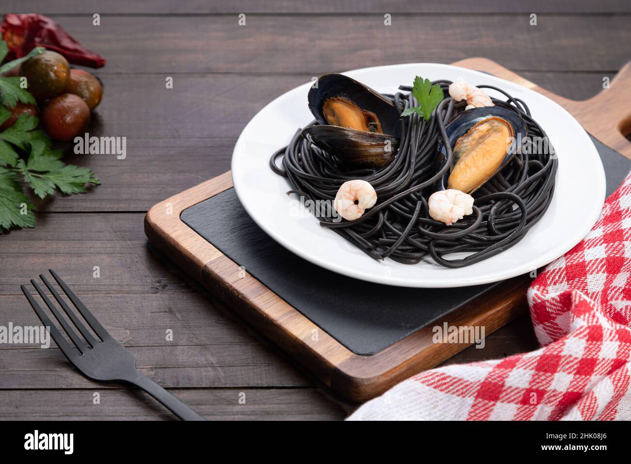 Teller mit schwarzer Pasta mit Meeresfrüchten auf Holzhintergrund. Mediterranes Speisekonzept. Stockfoto
